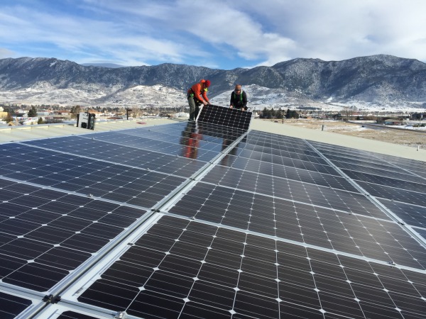 Our installers laying down the last solar module in front of the mountainous backdrop of Butte, MT 