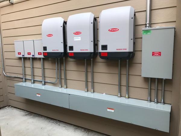 Three Fronius Symo 15 kW inverters, mounted outside on a well-protected wall