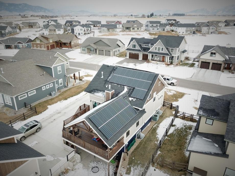 A drone shot of a residential solar array in Bozeman with snow on the roof and ground.